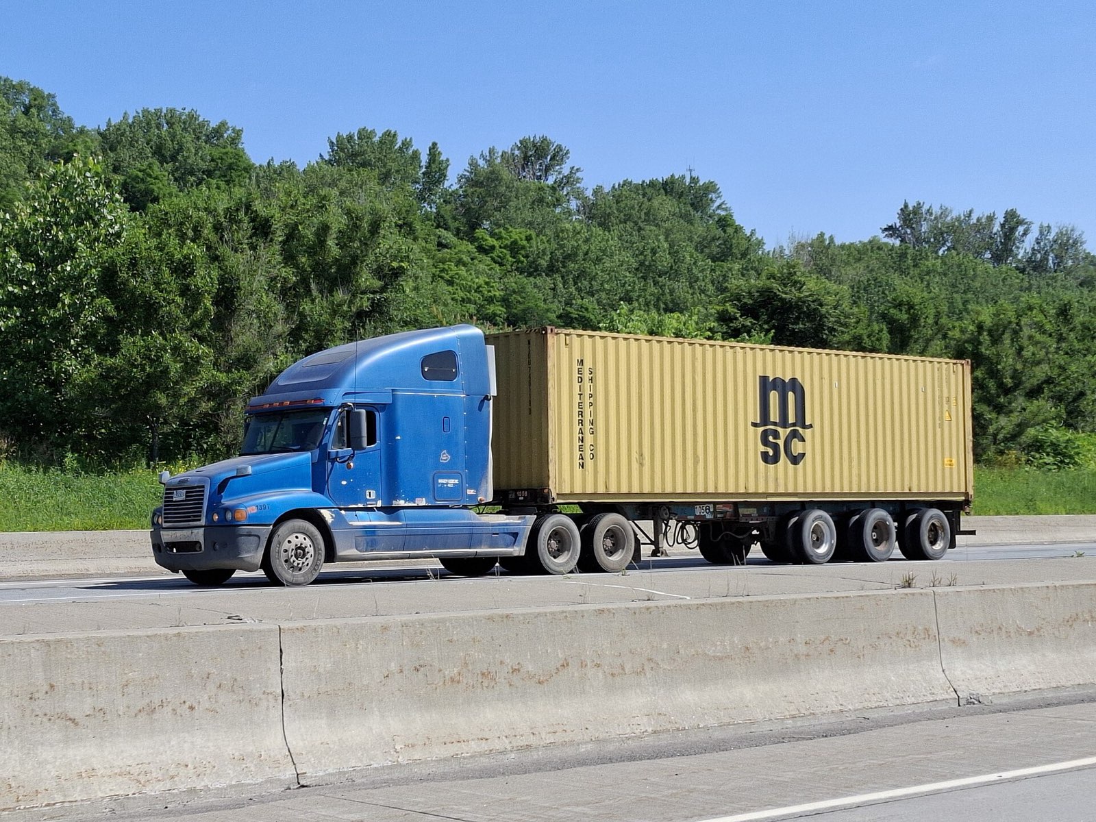 Semi truck hauling a shipping container on the highway